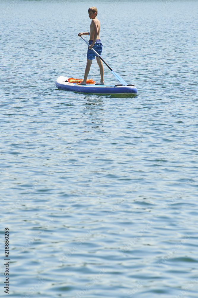 Paddle boarder. Child boy paddling on stand up paddleboard. Healthy lifestyle. Water sport, SUP surfing tour in adventure camp on active family summer beach vacation.