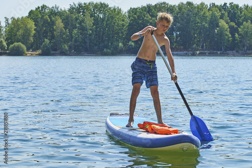 Paddle boarder. Child boy paddling on stand up paddleboard. Healthy lifestyle. Water sport  SUP surfing tour in adventure camp on active family summer beach vacation.