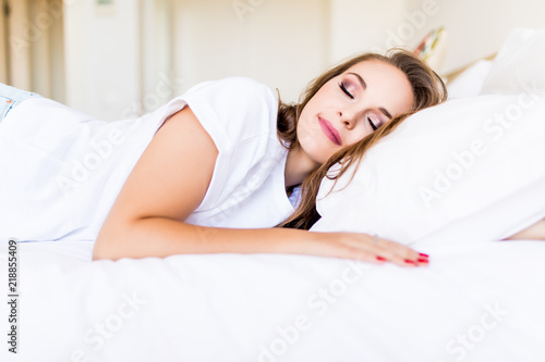Beautiful young brunette woman sleeping in a white bed.