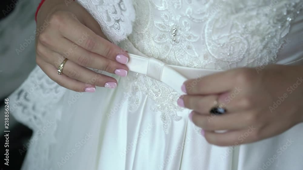 Young bride fixing and touching belt on wedding dress Young bride fixing and touching belt on wedding dress