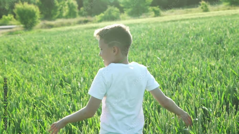 Happy boy running in green wheat field. Slow motion Happy boy running in green wheat field. Slow motion