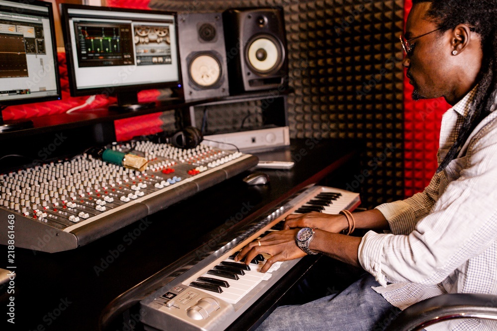 Fototapeta premium African man playing on synthesizer in recording Studio