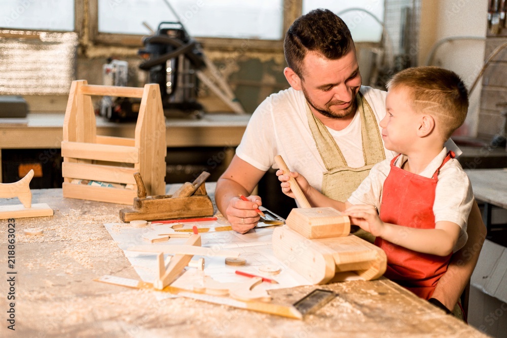 Dad and son in the carpenter's shop make wooden toys learning carpentry craft Dad and son in the carpenter's shop make wooden toys learning carpentry craft