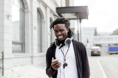 Canvas-taulu African man with dreadlocks walking down the street with headphones