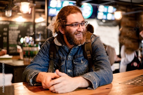 Photos Hairy male traveler in a denim jacket at a cafe