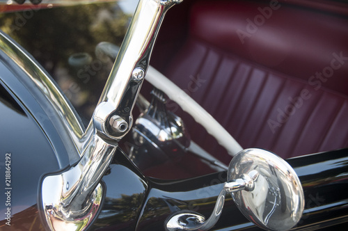 closeup of vintage automobile in black with red leather upholstery and lots of chrome