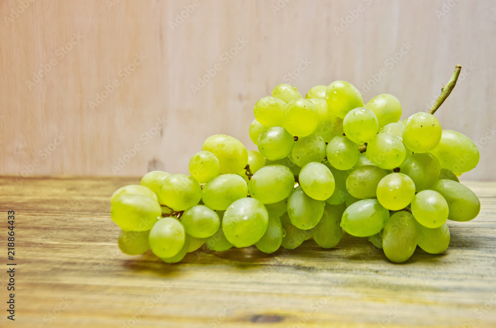 brush of green grapes on wooden background brush of green grapes on wooden background