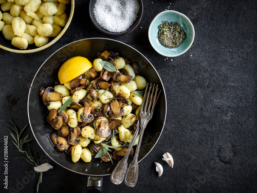 Prepared mushrooms and gnocchi dish on dark background with blank space,selective focus photo