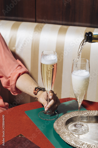 A glass of prosecco held by a girl in an elegant bar with vintage pop colors