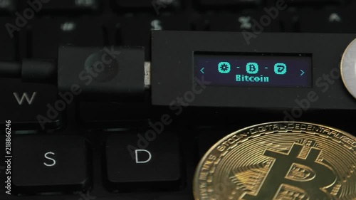 Cold hardware wallet for crypto. Connected to a computer to store Bitcoin, Litecoin and other cryptocurrencies.Notebook, Laptop keys in the background. Vires in numeris. Strobe effect on display.