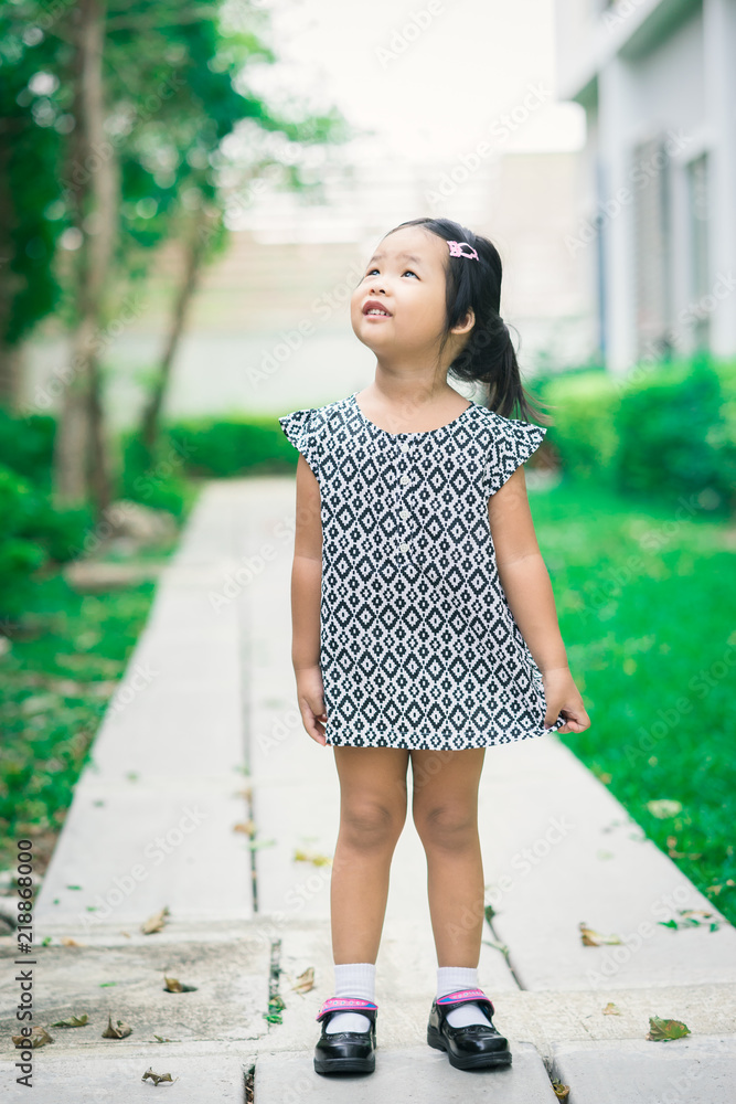 Portrait of happy asian little girl in dress standing on footpath in the park Portrait of happy asian little girl in dress standing on footpath in the park