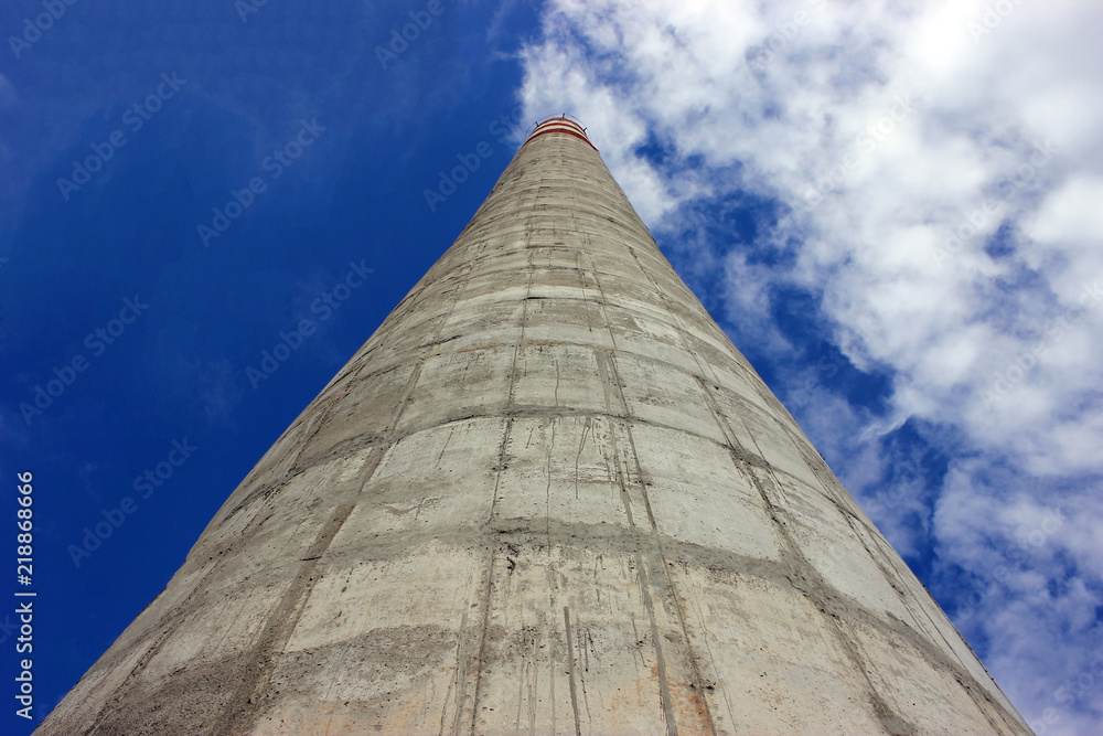 large factory concrete chimney. Steam escapes from the pipe against the sky. Industrial emissions of pollutants into the atmosphere. large factory concrete chimney. Steam escapes from the pipe against the sky. Industrial emissions of pollutants into the atmosphere.