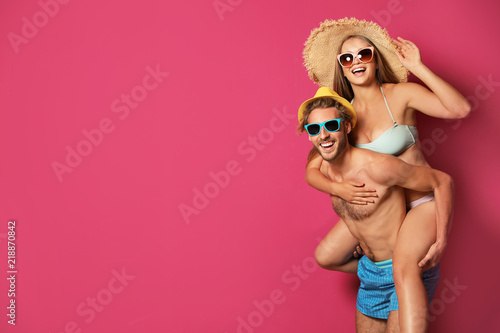 Happy young couple in beachwear on color background. Space for text