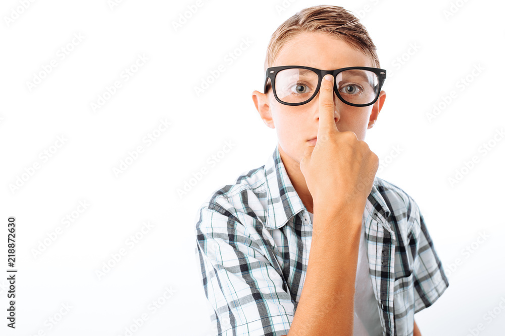 Handsome teen boy straightens glasses, male nerd in Studio on white background