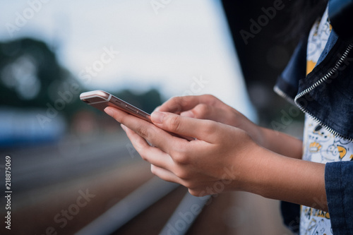 Close-up image of male hands using smartphone on city shopping street, searching or social networks concept, hipster man typing an sms message to his friends