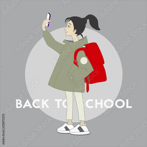 Back to school.Cute schoolgirl in green coat with backpack and phone.