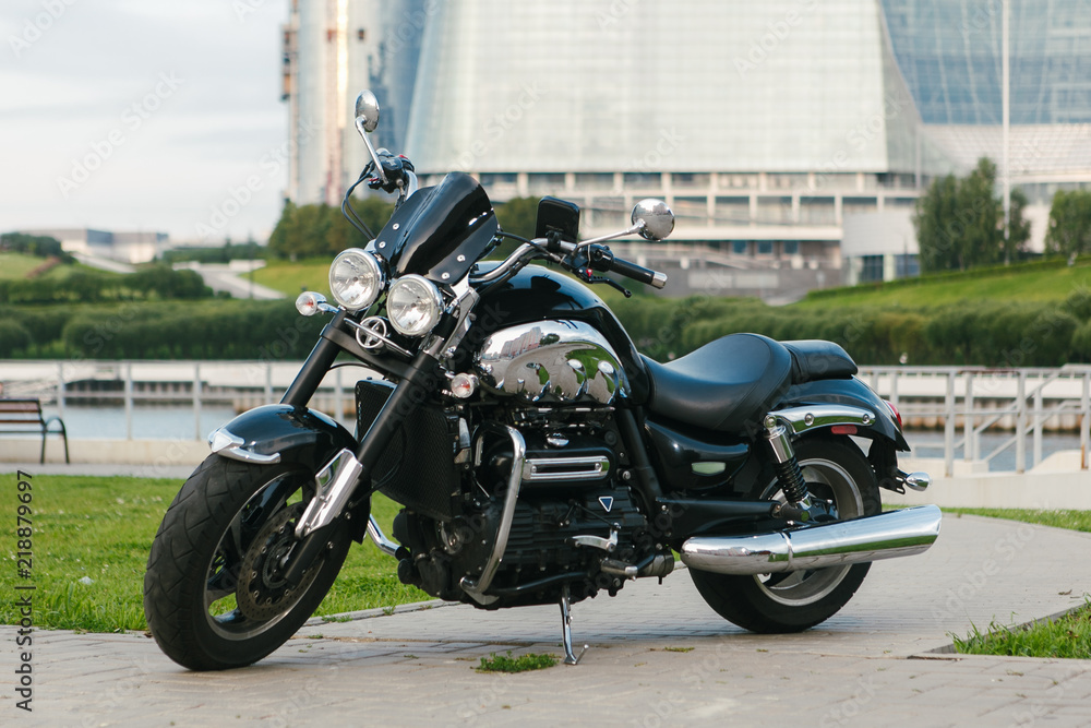 Middle shot of a black motorcycle in front of a city river.