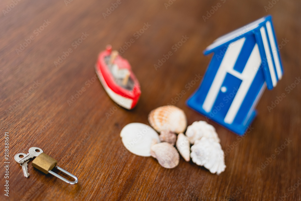 Padlock and keys of a beach house next to wooden toy house with maritime motives. Padlock and keys of a beach house next to wooden toy house with maritime motives.