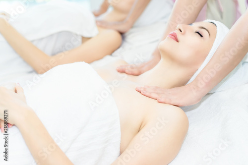 Spa facial massage in beauty salon.Beautiful woman lying and relaxing on spa bed.Woman having wellness body massage and feeling visibly good at spa salon.