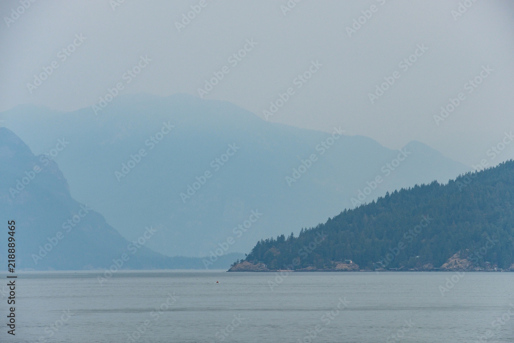 layered mountains behind Island near coast under the heavy smoke in the morning 