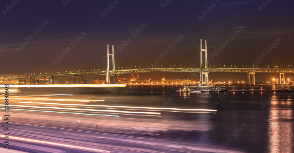 Fototapeta premium Panorama of Yokohama Bay Bridge from Ōsanbashi Pier with boats speed lights in the Minato Mirai district of Yokohama with boats under the night sky.
