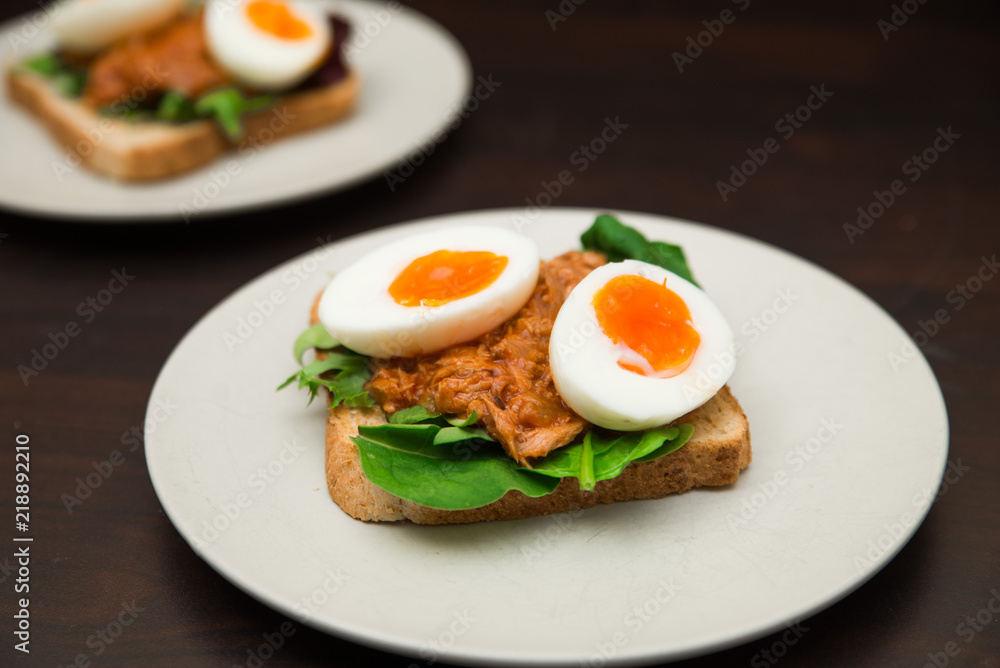 Healthy natural high protein snack whole grain toast with soft boiled egg, tuna and spinach