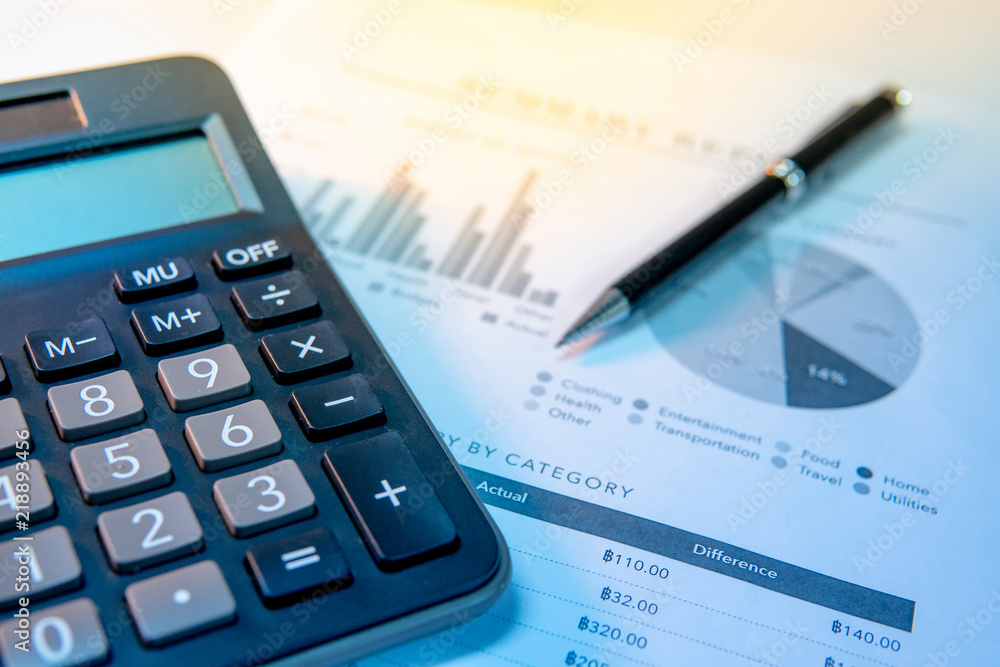 Calculator, pen and summary report paperwork with bar graph, pie chart and table. Financial data analysis. Business planning and management concept Calculator, pen and summary report paperwork with bar graph, pie chart and table. Financial data analysis. Business planning and management concept