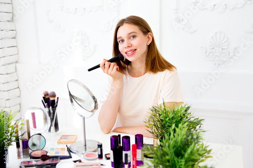 A portrait of woman with makeup brushes near face