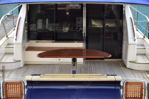 Fotografija Wide stern deck with outdoor table and tinted glass door of large luxurious power catamaran