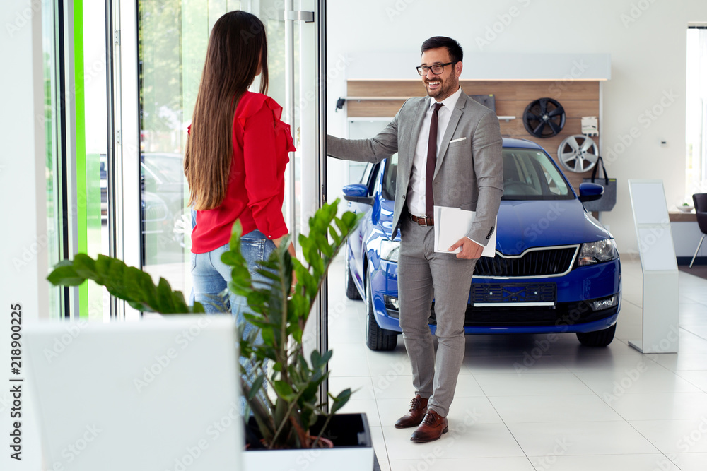 Φωτογραφία Happy girl enjoys buying a new car in the showroom