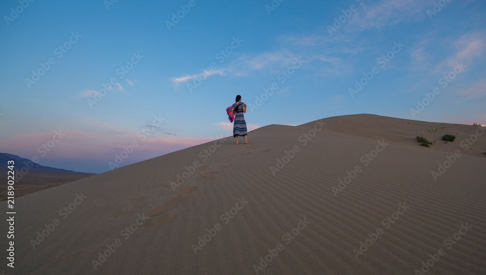young girl in a dress on a sand dune at sunset
