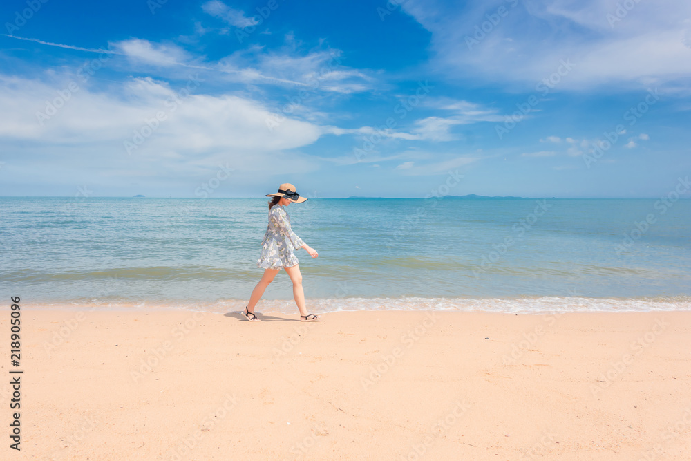 The woman is happily walking on the beach.