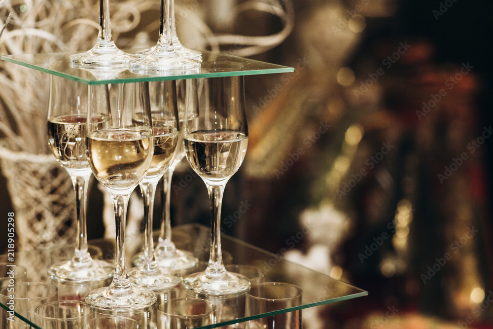 Elegant champagne glasses catering, tiered alcohol drinks on glass table, business dinner party reception in luxury restaurant close-up, catering concept Elegant champagne glasses catering, tiered alcohol drinks on glass table, business dinner party reception in luxury restaurant close-up, catering concept