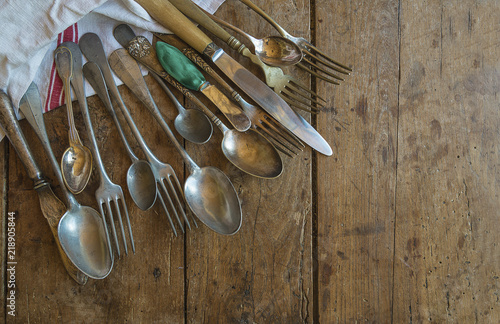 Various of vintage cutlery and linen napkin on old wooden background with copy space