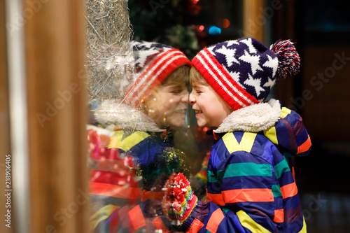 Funny happy child in fashion winter clothes making window shopping decorated with gifts, xmas tree © Irina Schmidt