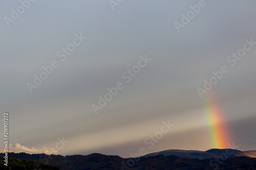 Beautiful and surreal view of part of a rainbow over some hills