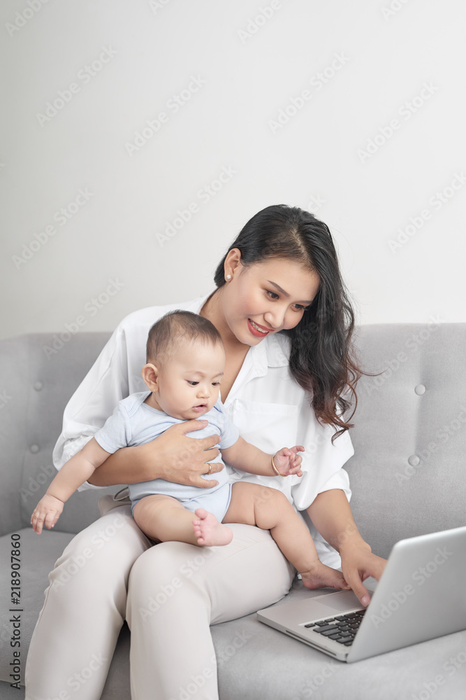 Young mother holding baby while working in home office