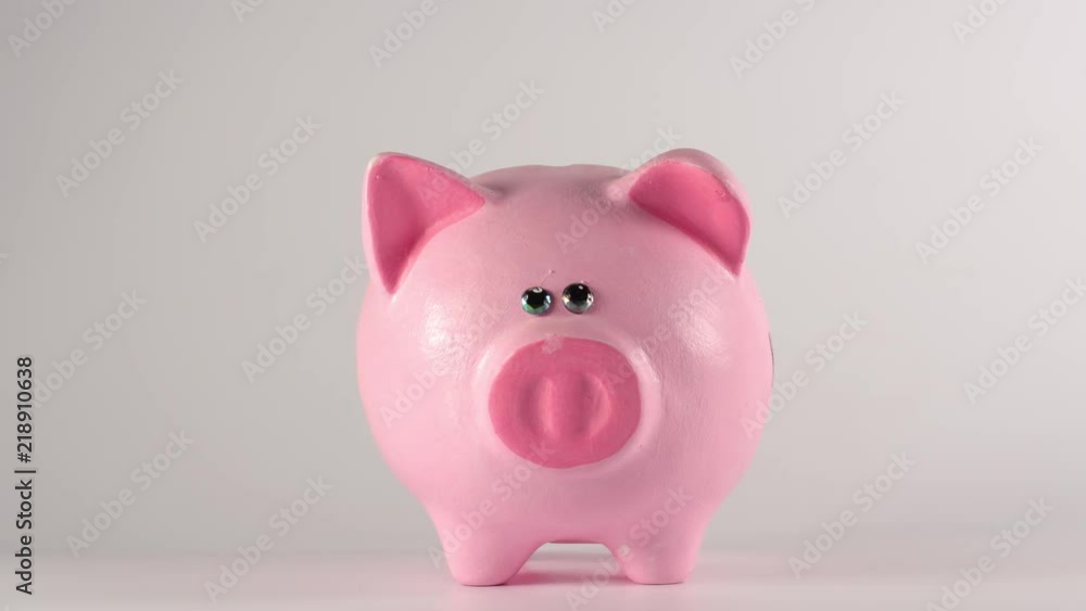 TIME-LAPSE: Male hand throws coins into a pink piggy moneybox TIME-LAPSE: Male hand throws coins into a pink piggy moneybox