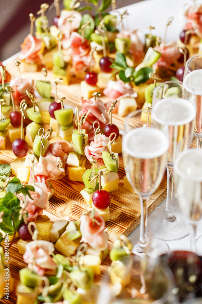 solemn happy new year banquet. Lot of glasses champagne or wine on the table in restaurant. buffet table with lots of delicious snacks. canapes, bruschetta, and little desserts on wooden plate board