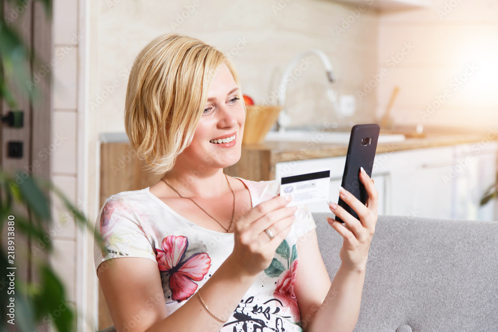 Pretty blonde woman sitting on the sofa and making shopping with the smartphone, online purchase concept Pretty blonde woman sitting on the sofa and making shopping with the smartphone, online purchase concept