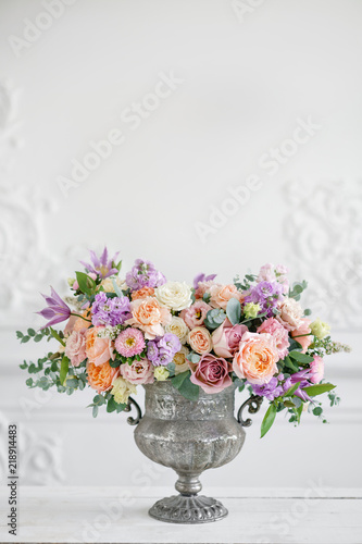 Gorgeous bouquet of different flowers. floral arrangement in vintage metal vase. table setting. lilac and peach color