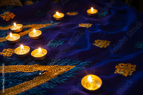 Flame candle lamps for the evening prayers. Diwali lighting on blue sari with golden embroidery