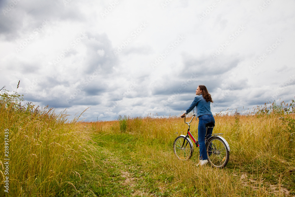 Happy Young Woman riding bicycle on a yellow field. Healthy Lifestyle.