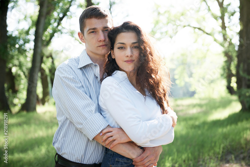 young couple walking in the forest, summer nature, bright sunlight, shadows and green leaves, romantic feelings