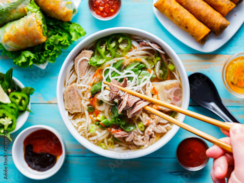 eating colorful vietnamese pho bo with chopsticks from top down view