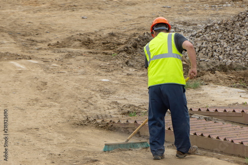 Worker at the construction site cleans the carriageway with a brush