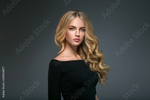 Vászonkép Blonde hairstyle woman beauty with long curly blonde hair over dark background