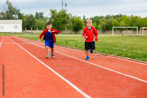 two boys running on sports tracks in the stadium