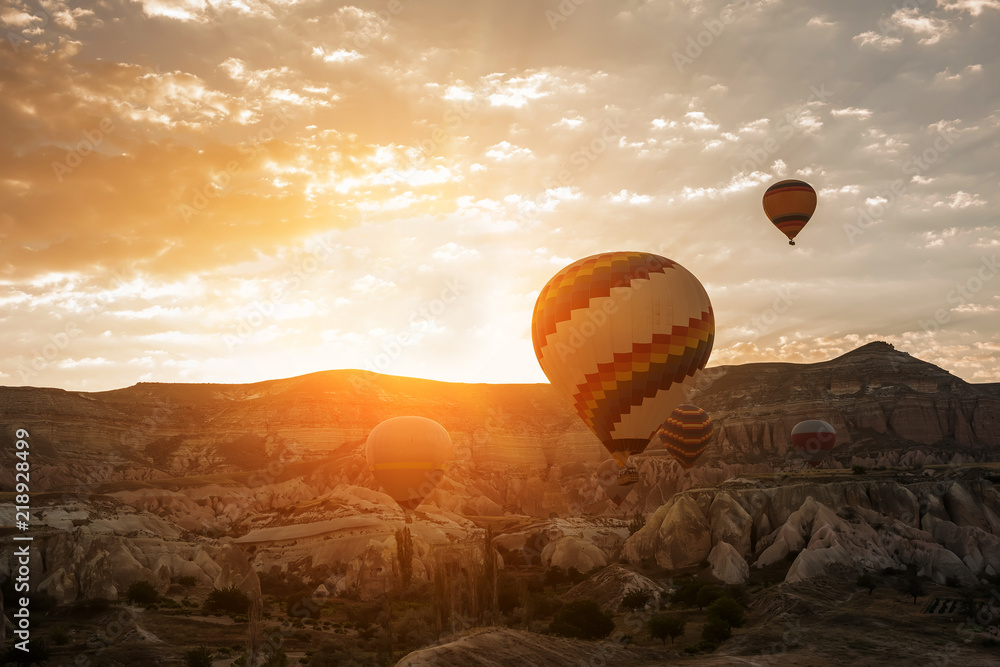 Balloons against the background of rocks at dawn. Huge multicolored balls in the sunlight of dawn. Turkey. Cappadocia. Goreme National Park.
