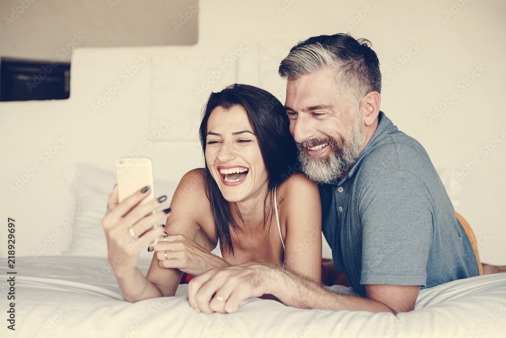 Couple using a smartphone in bed Couple using a smartphone in bed